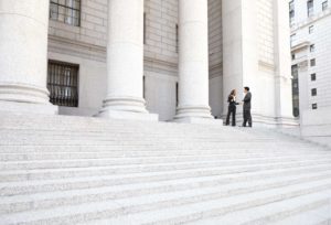 Two well dressed professionals in discussion on the exterior steps of a courthouse