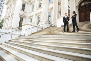 man and woman converse on the steps of a legal or municipal building